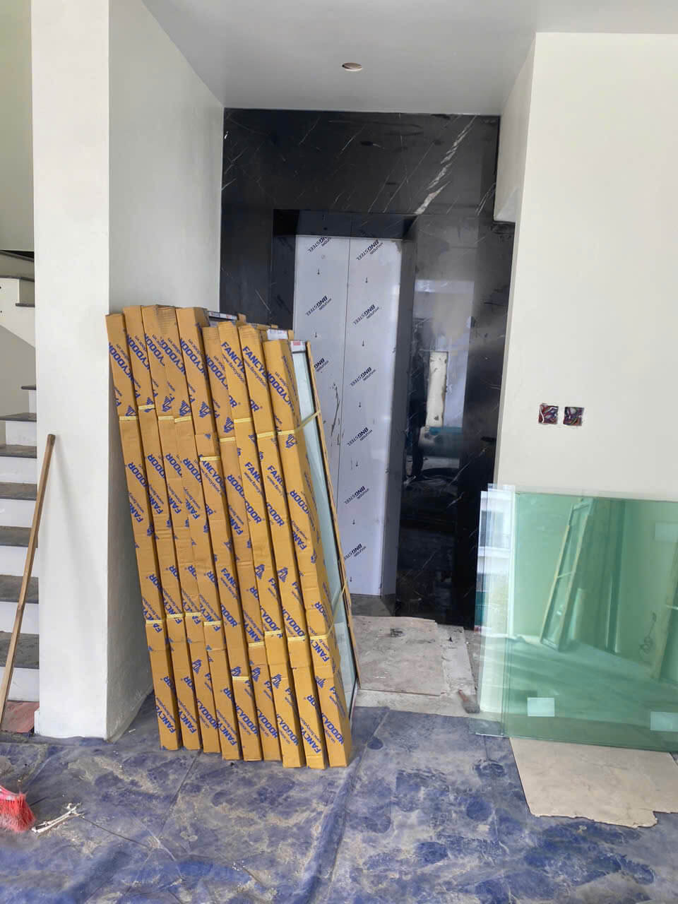 Kính cường lực và hộp nhôm kính Nanodoor xếp cạnh thang máy trong nhà đang thi công